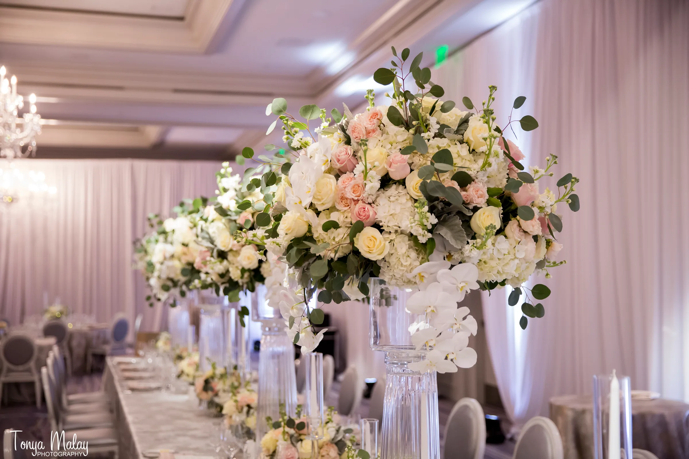 Tall blush and cream centerpieces running the length of a ballroom reception table