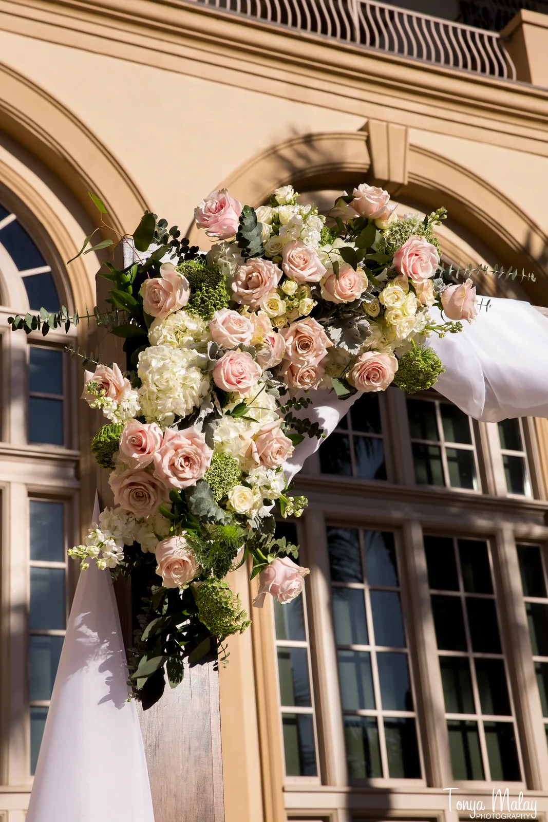 Corner spray of blush roses and hydrangea on a draped arch